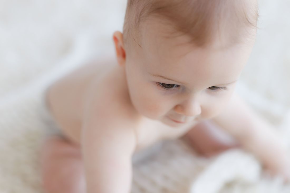 A baby looking down in soft focus, surrounded by white