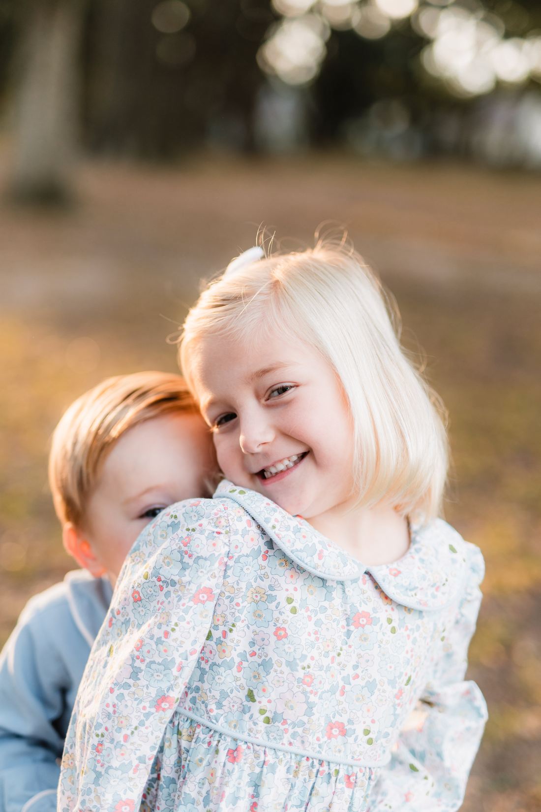A girl hugging her little brother in a field