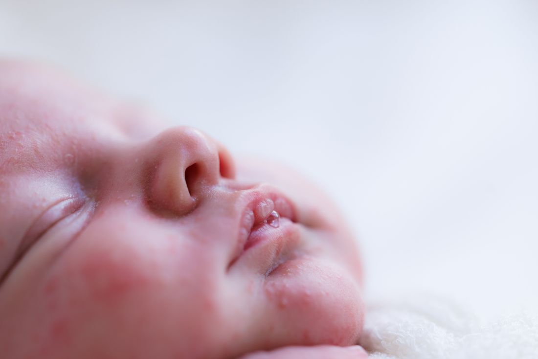 Close-up of a sleeping newborn's face turned to the side on a white blanket