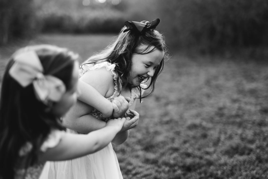 Black and white photo of two sisters doubled over laughing together