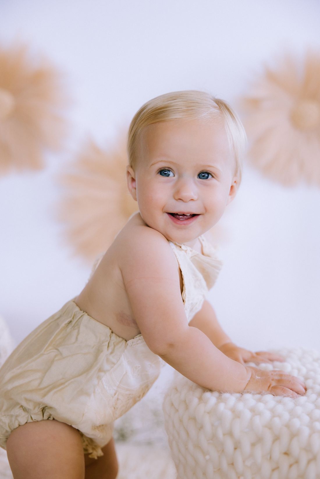 A one-year-old pulling up to stand in the studio