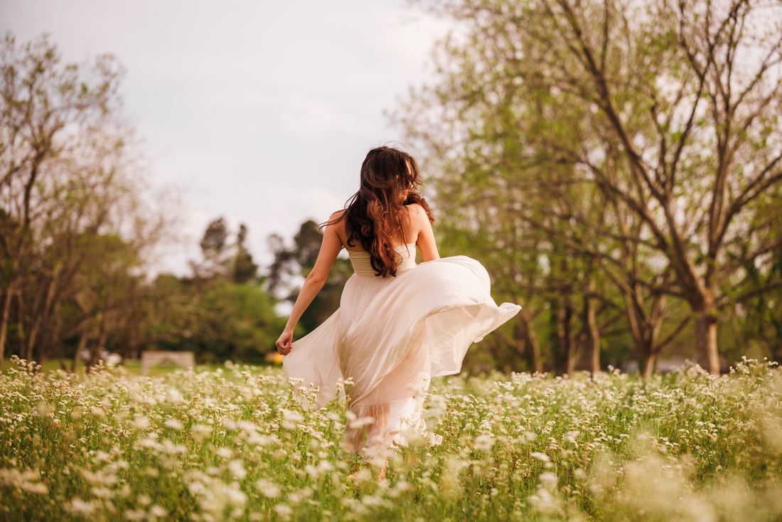 A senior turning through a wildflower meadow with her skirt sweeping behind her