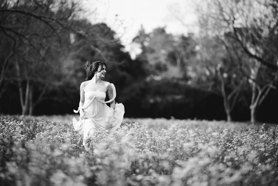 Black and white photo of a senior walking through a field of blossoms