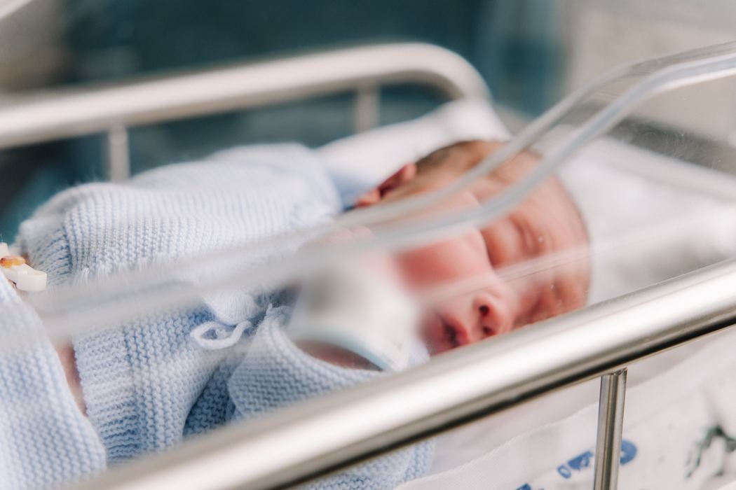 A newborn asleep in the hospital bassinet with his name band on his wrist