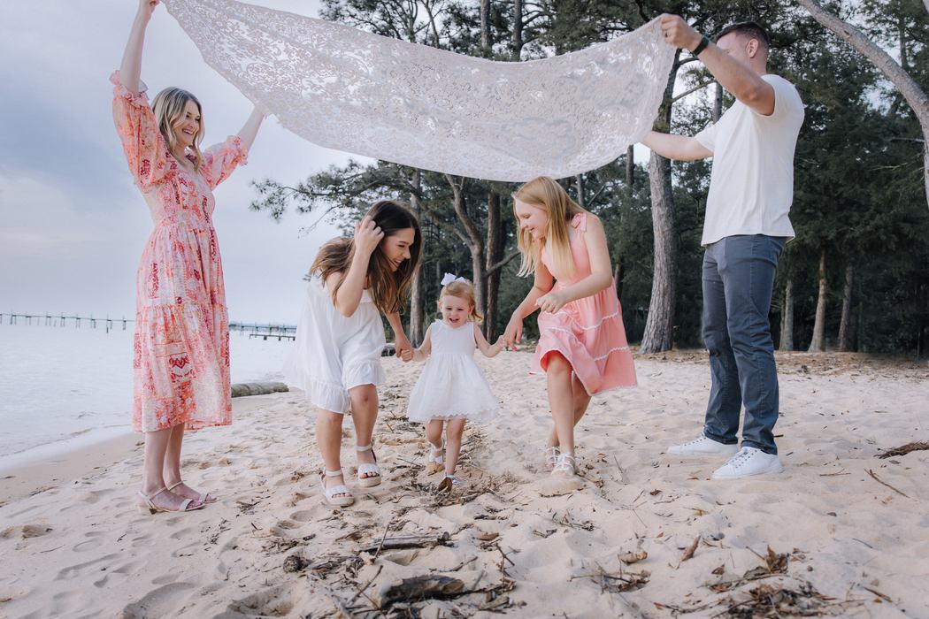 A family playing on the bay shore under a lace blanket