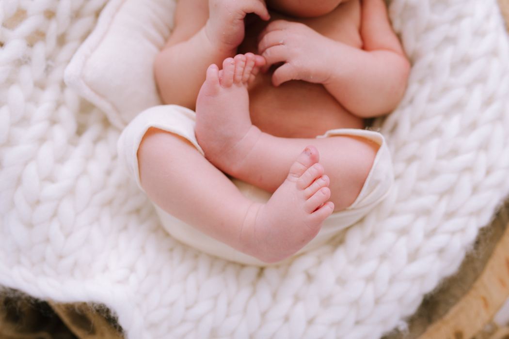 Close-up of a newborn's feet and toes against a chunky knit blanket