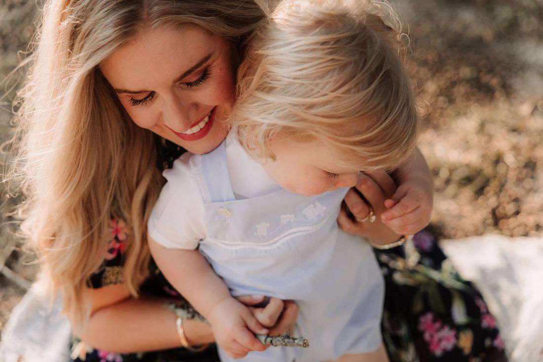 A mother laughing down at the toddler on her hip in the late afternoon sun