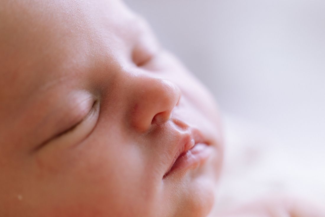 Close-up of a sleeping newborn's profile, lashes and lips in soft focus